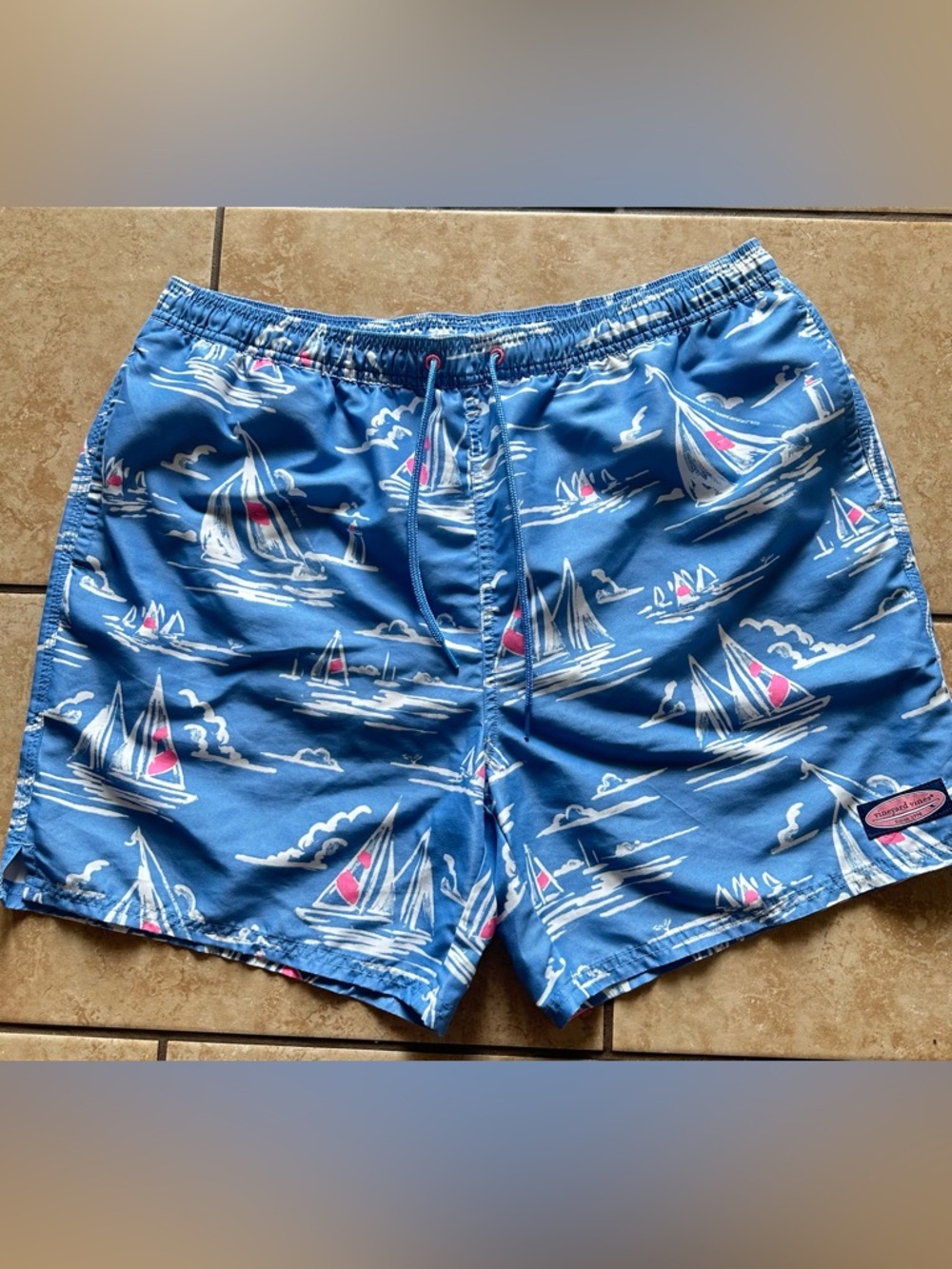 Vineyard Vines sailboat print men's swim trunks in hot pink and blue.